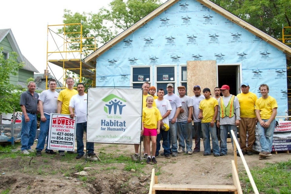 Midwest & Habitat For Humanity team standing in front of a house prepped for siding.