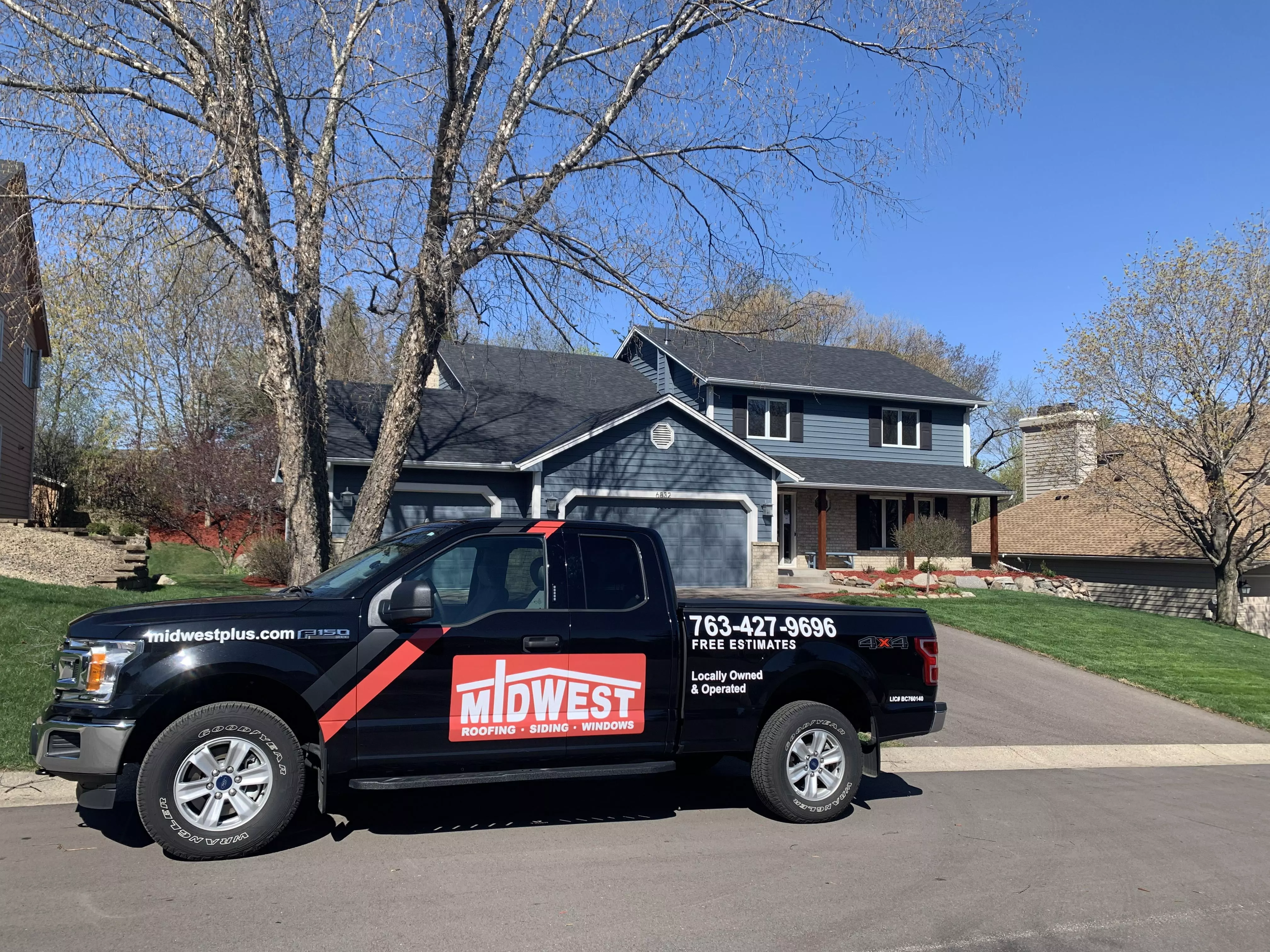 A Midwest Roofing, Siding & Windows service vehicle in front of a home with a new roof and new siding.