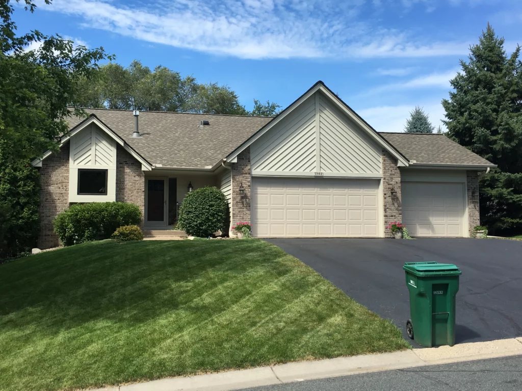 A home with a new shingle roof installed by Midwest Roofing, Siding and Windows.  The front yard is a lush green.