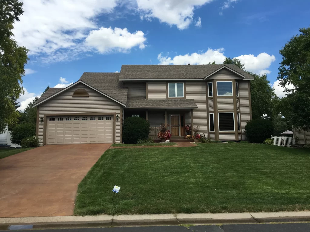 A two story brown home near Minneapolis, Minnesota with a new asphalt shingle roof and new windows installed by Midwest Roofing, Siding & Windows.